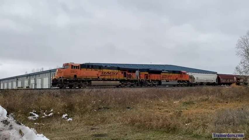Manifest freight train departing town amid cloudy/cool weather...